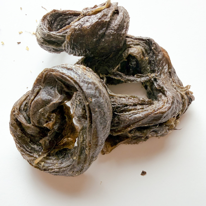 A pile of dried, curled pieces of halibut fish, photographed on a plain white background.