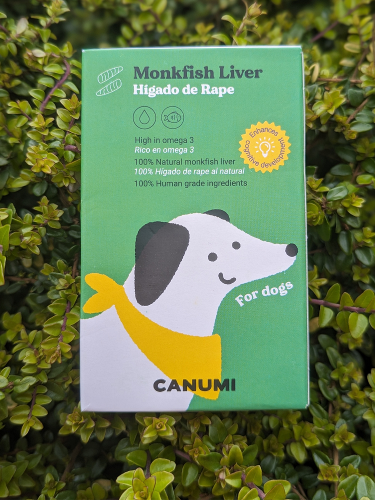 A packaged product labelled 'Monkfish Liver' for dogs, with the brand 'CANUMI' displayed prominently. The packaging is green with an illustration of a white dog wearing yellow a bandana.