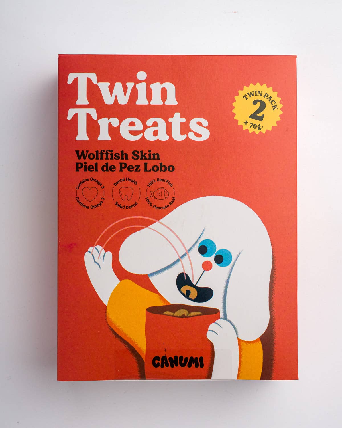 A twin pack box of Canumi Twin Treats Wolffish Skin, featuring a bright red background with a cartoon white dog character holding a bowl of treats.